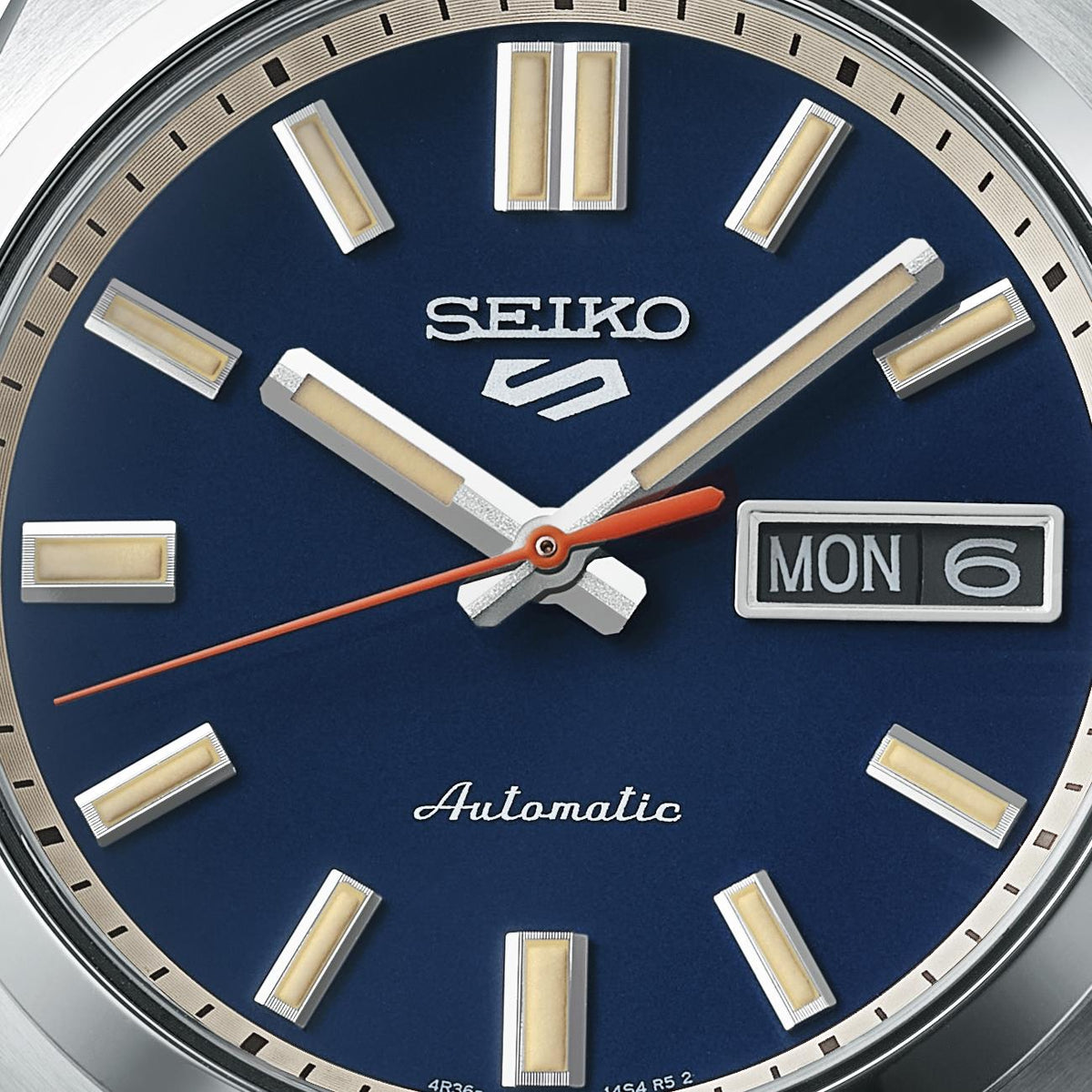 Close-up of the Seiko SNXS mens SRPK87K1 watch, highlighting the textured brand logo, day-date window, and automatic script on the dial surface.