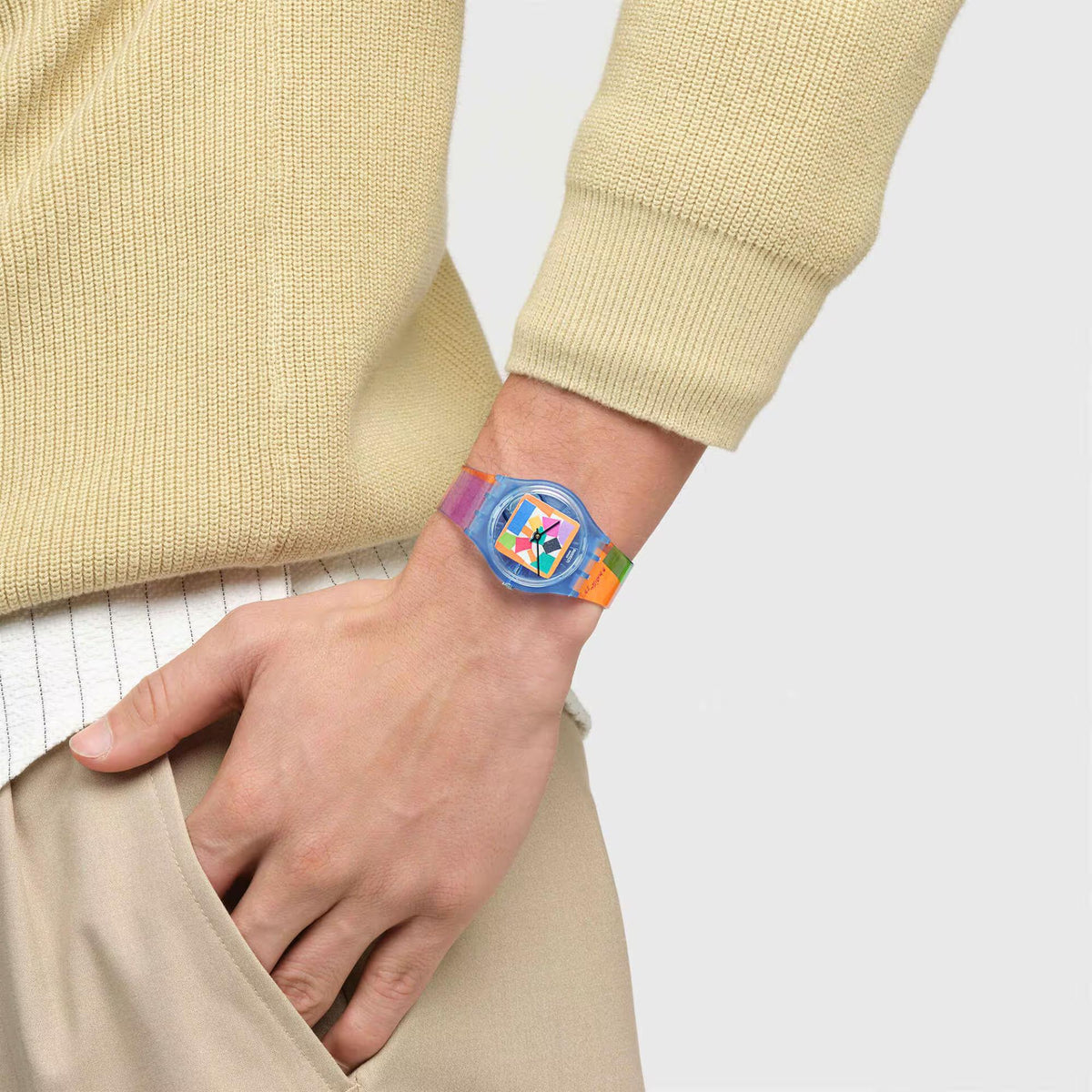 Swatch wristwatch on wrist with geometric dial and multicolor printed strap