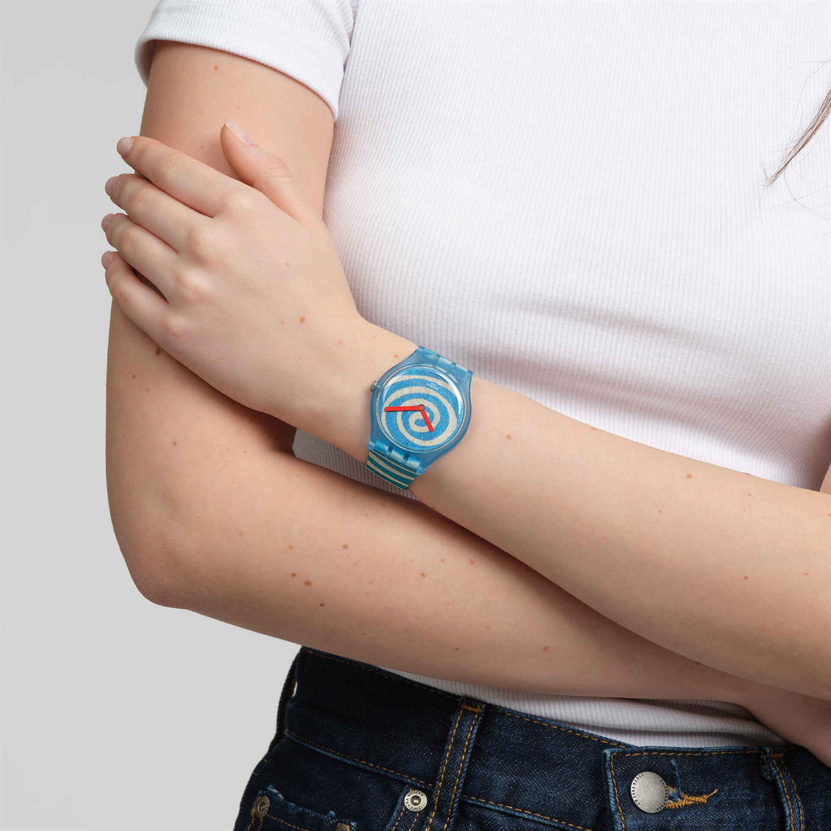 Silicone strap watch on wrist with blue spiral dial, red hands, and striped band