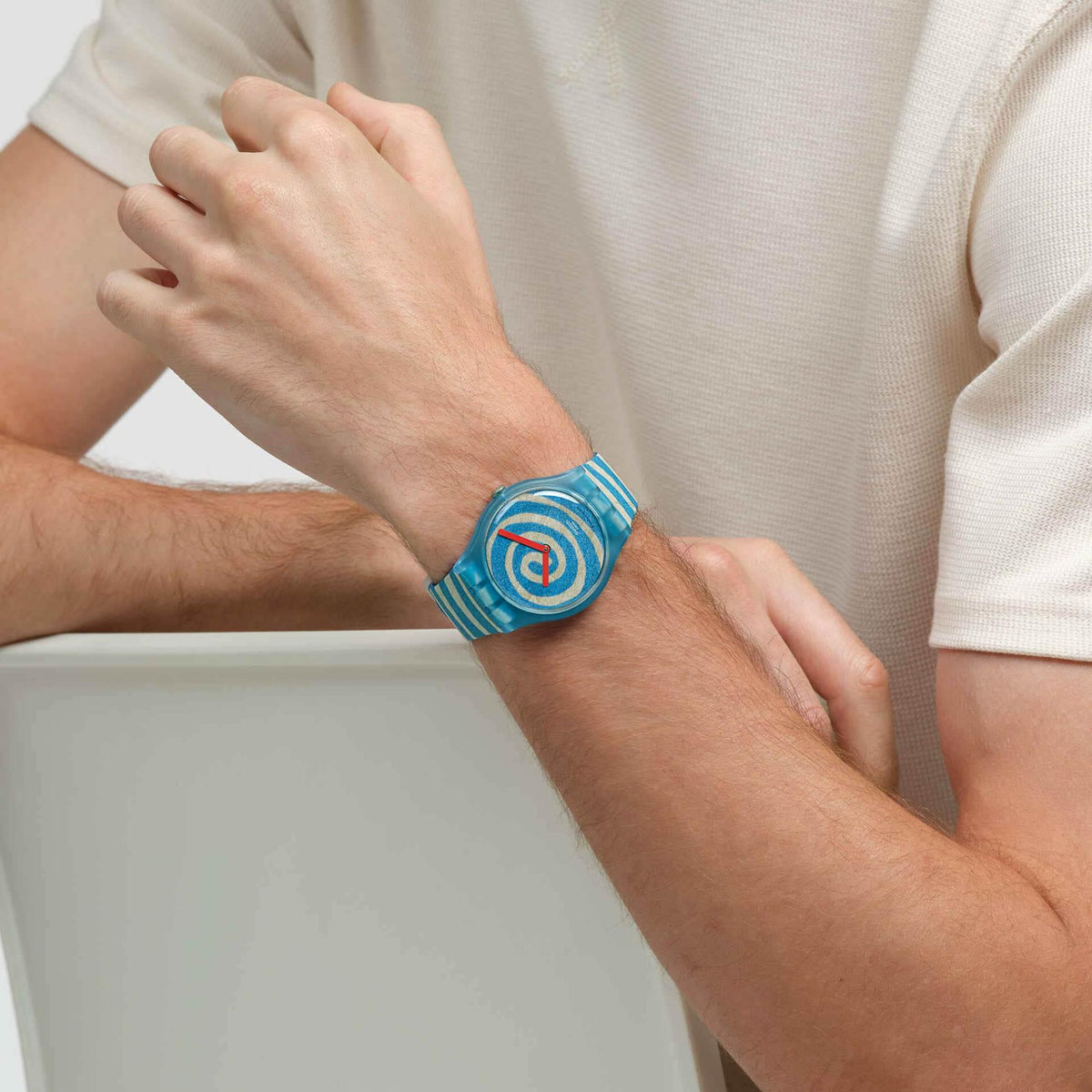 Silicone strap watch on wrist showing blue spiral dial and striped band detail