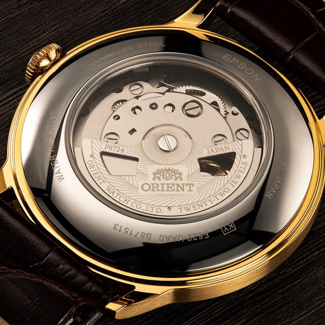 Gold-tone watch caseback with see-through movement window and brown leather strap