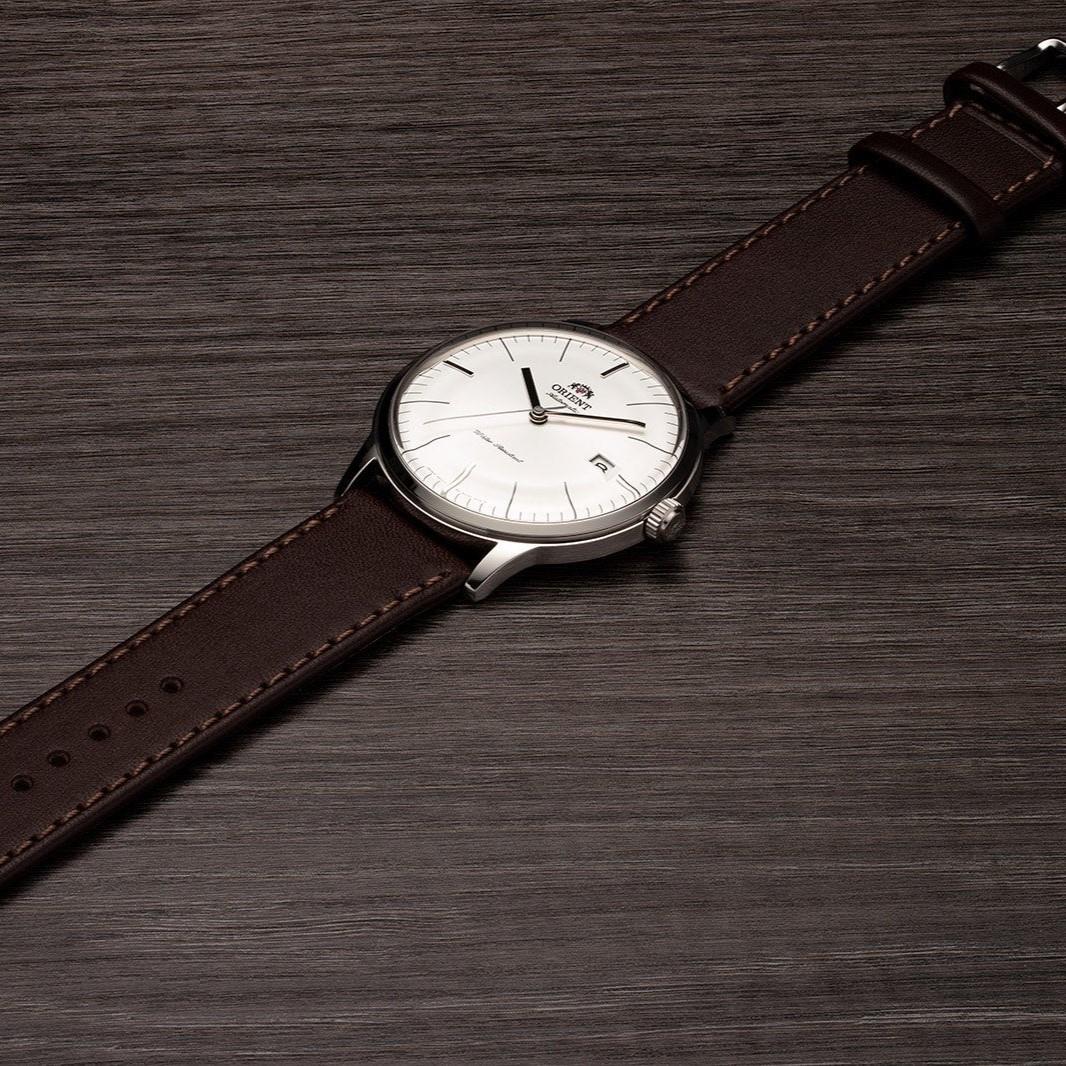 Men's automatic wrist watch on brown leather strap with white dial and slim silver case