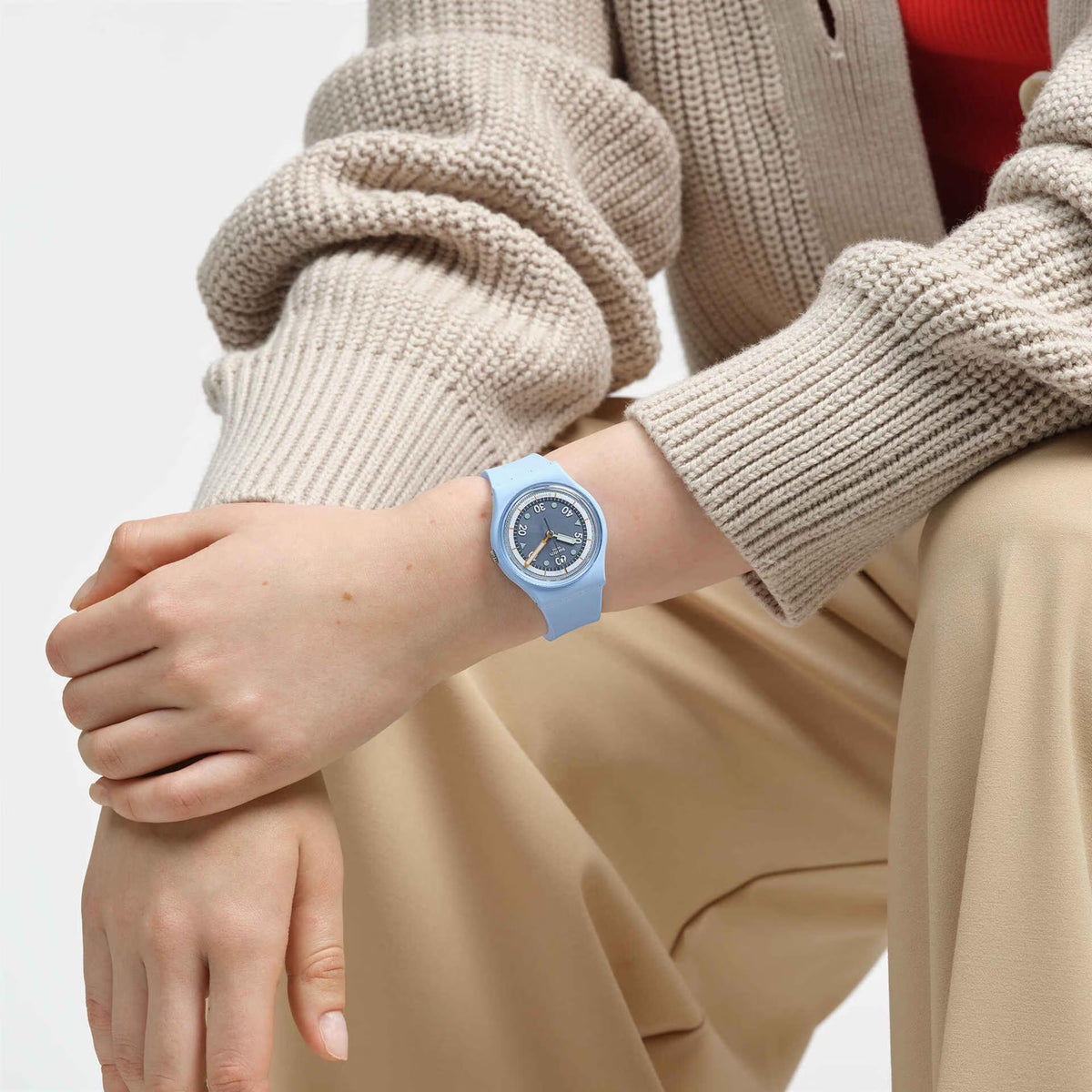 Light blue silicone watch on wrist with dark dial and orange hand accents