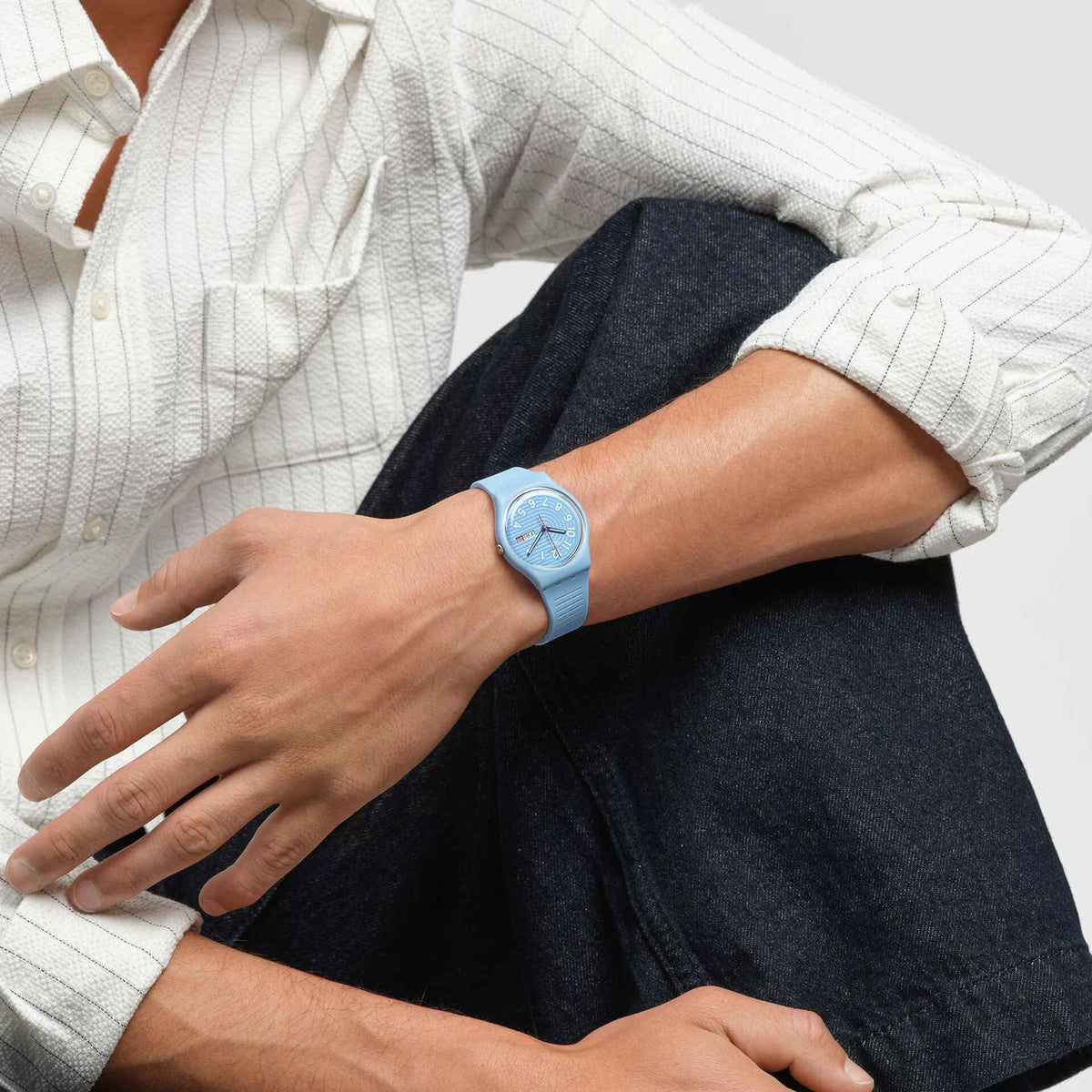 Light blue silicone strap watch on wrist, gray dial with red/blue hands and date window