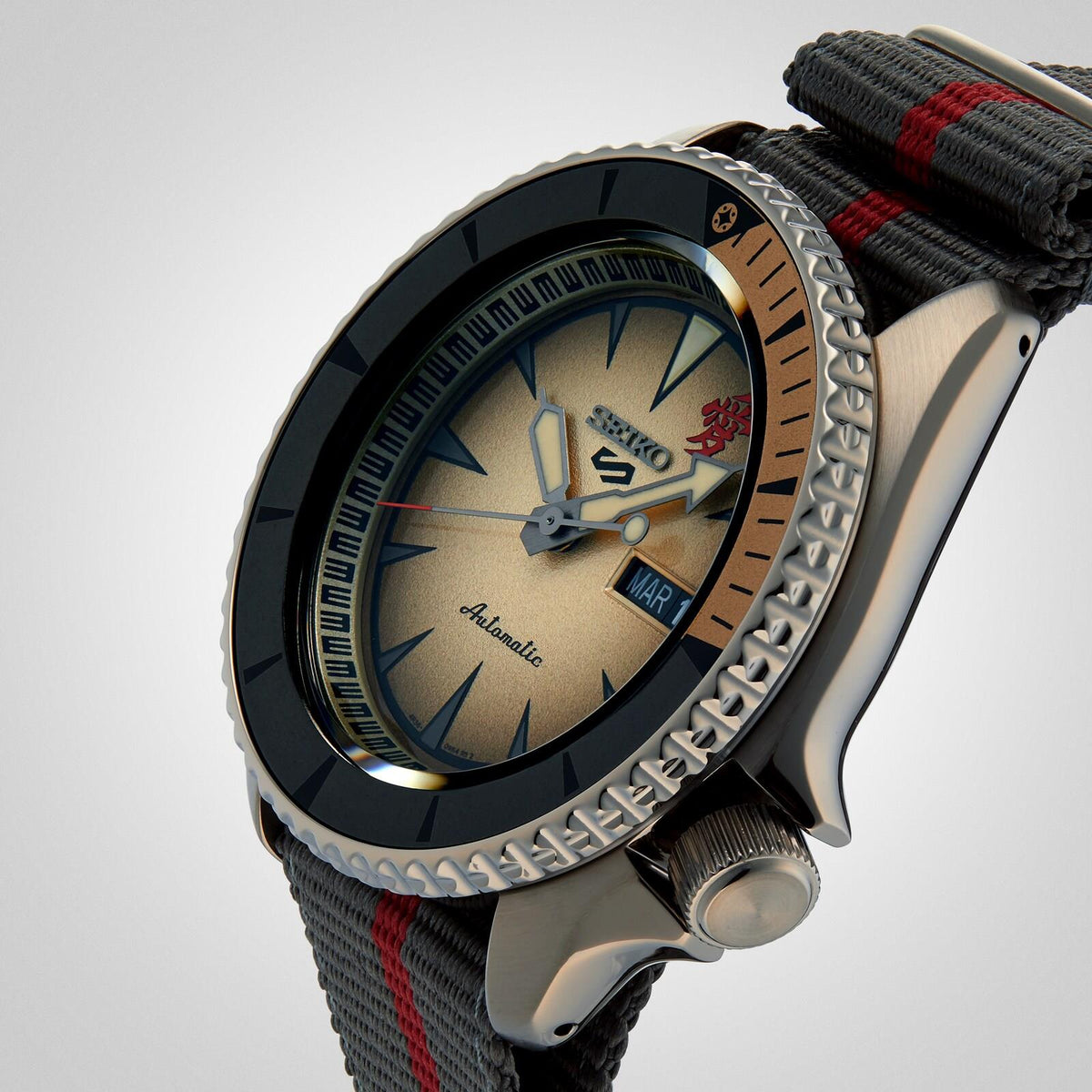 Side view of a Seiko automatic watch highlighting the textured bezel, cream face, and grey nylon strap.