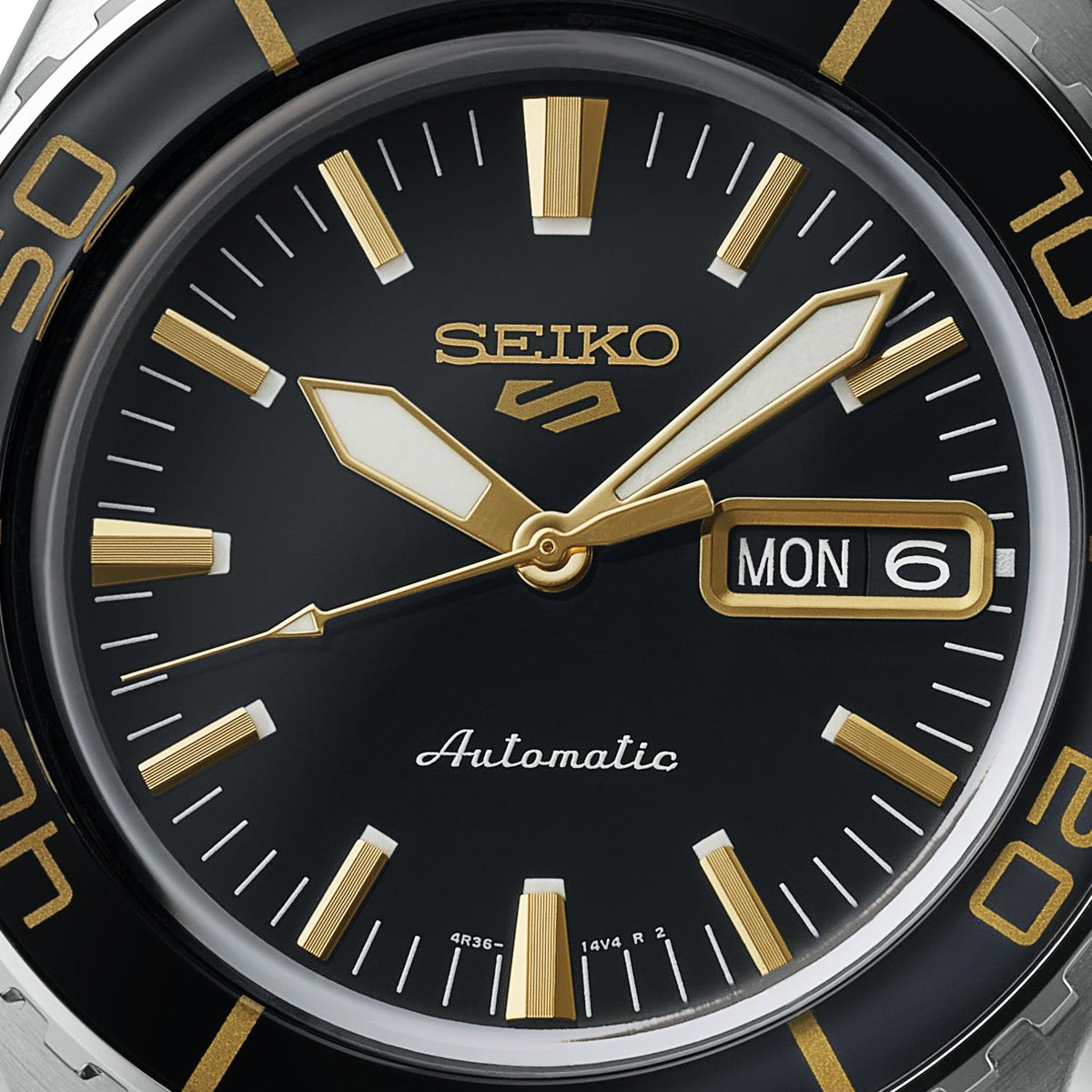 Close-up of the black watch face revealing detailed gold-toned hands, hour markers, and the day-date calendar display.