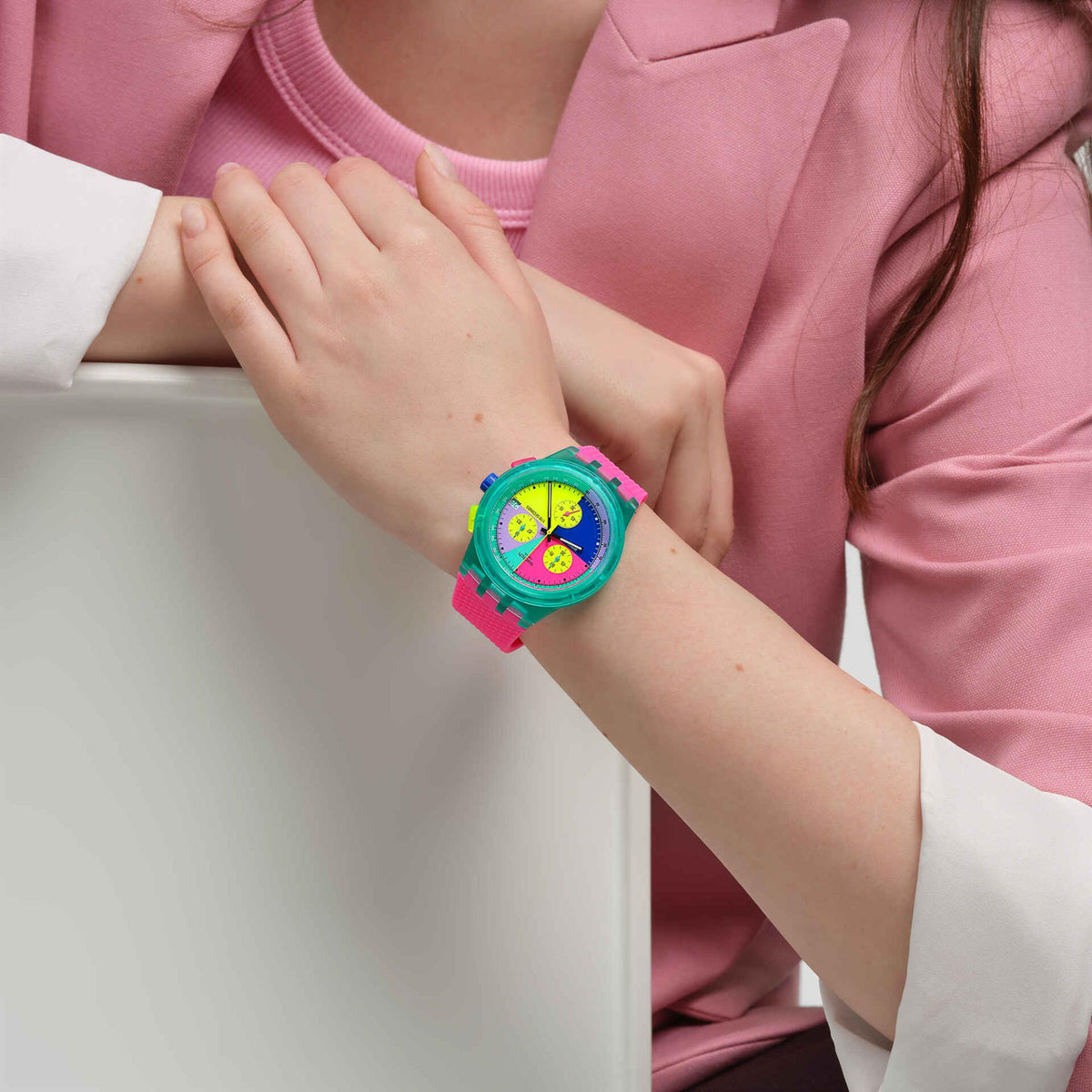 Pink silicone chronograph watch on wrist with neon multicolor dial and visible crown.