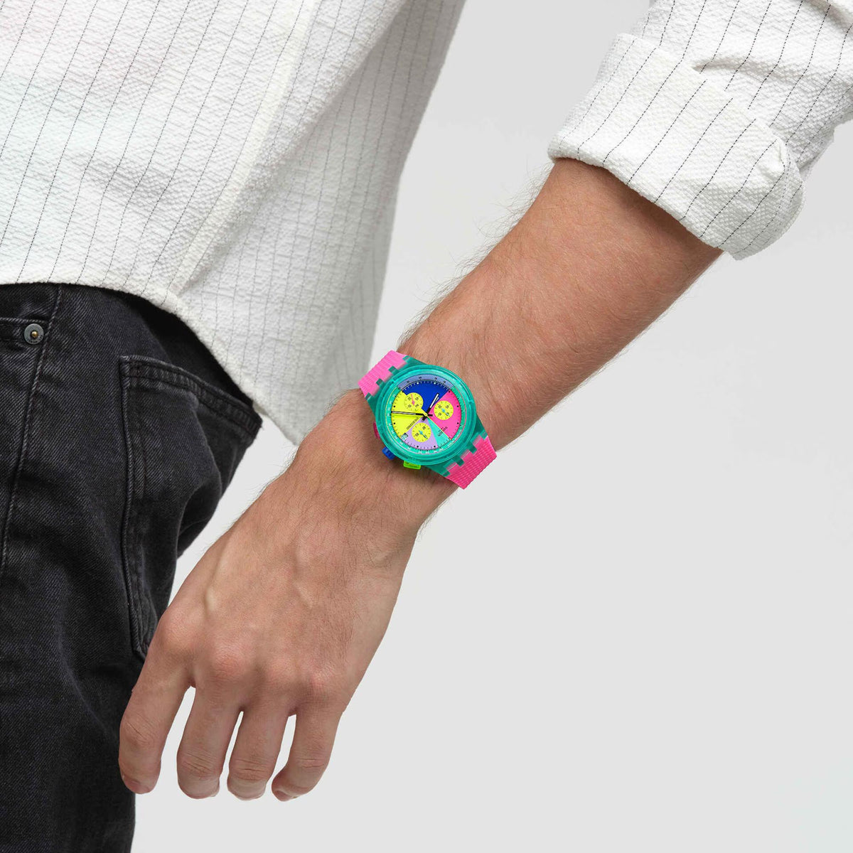 Multicolor chronograph watch on wrist with pink silicone band and bright circular neon dial.