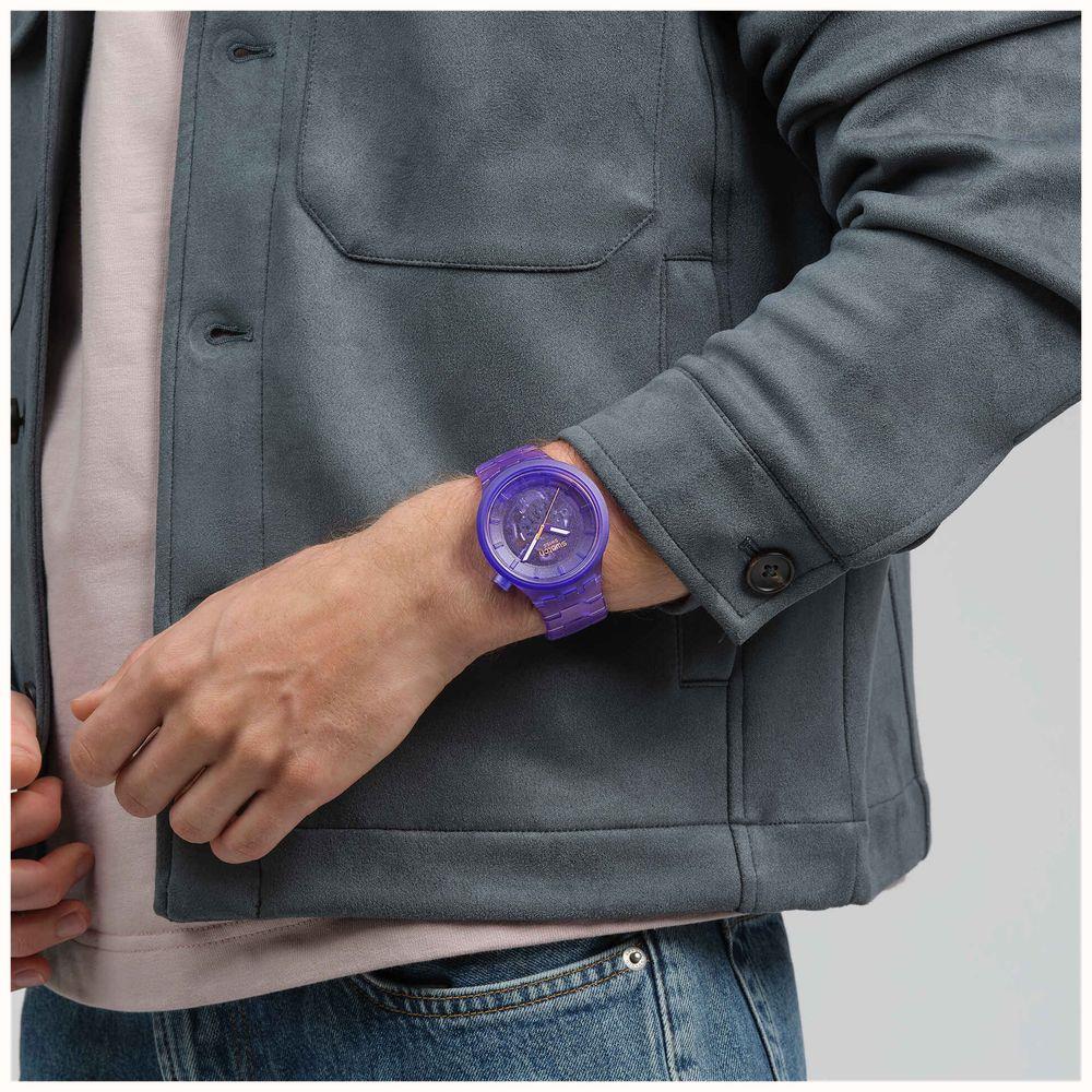 Purple Swatch strap watch on wrist, round dial with orange-tipped second hand