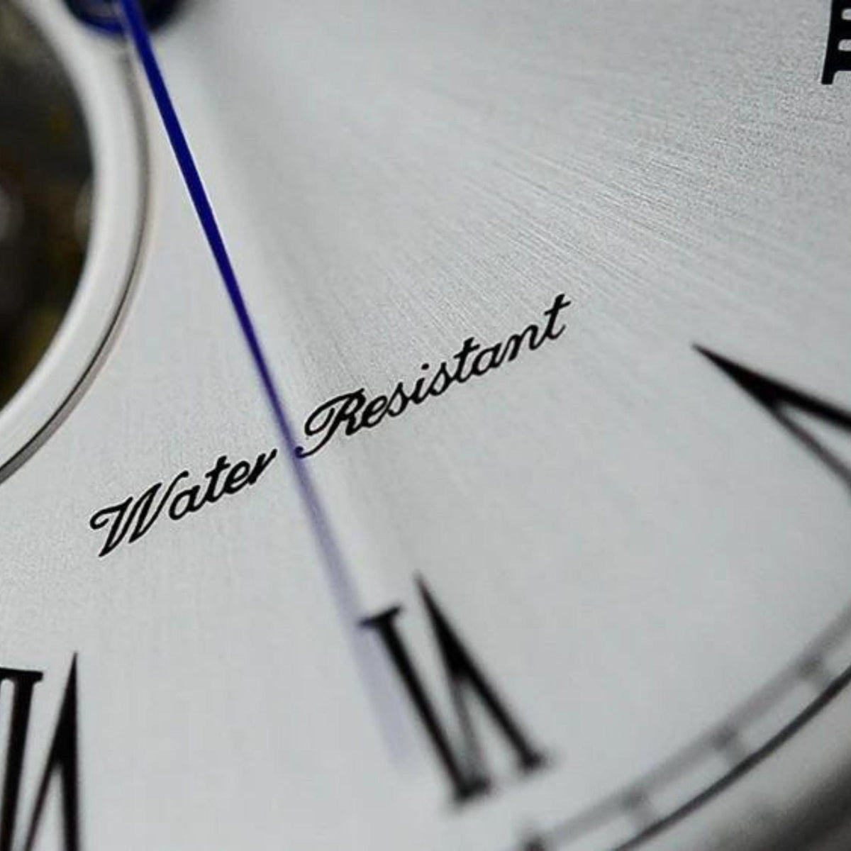 White watch dial detail showing Water Resistant text and Roman numeral markers
