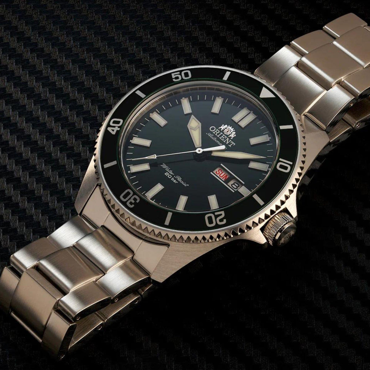 Stainless steel automatic watch with green dial, bezel numerals, and metal link bracelet.