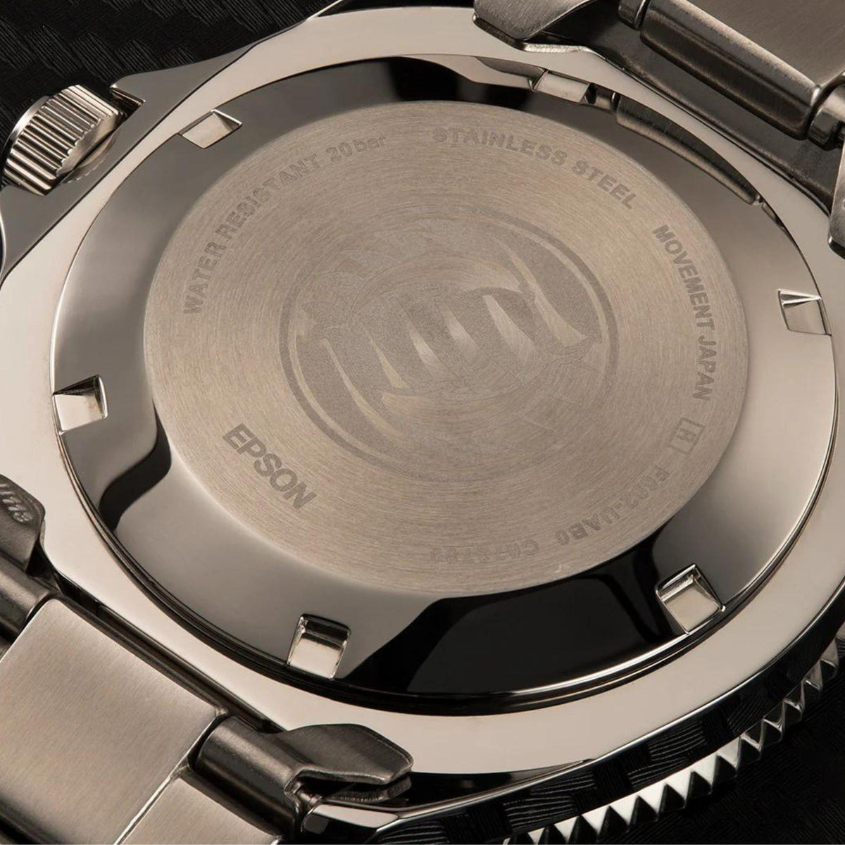 Stainless steel watch case back with engraved markings and knurled bezel edge.
