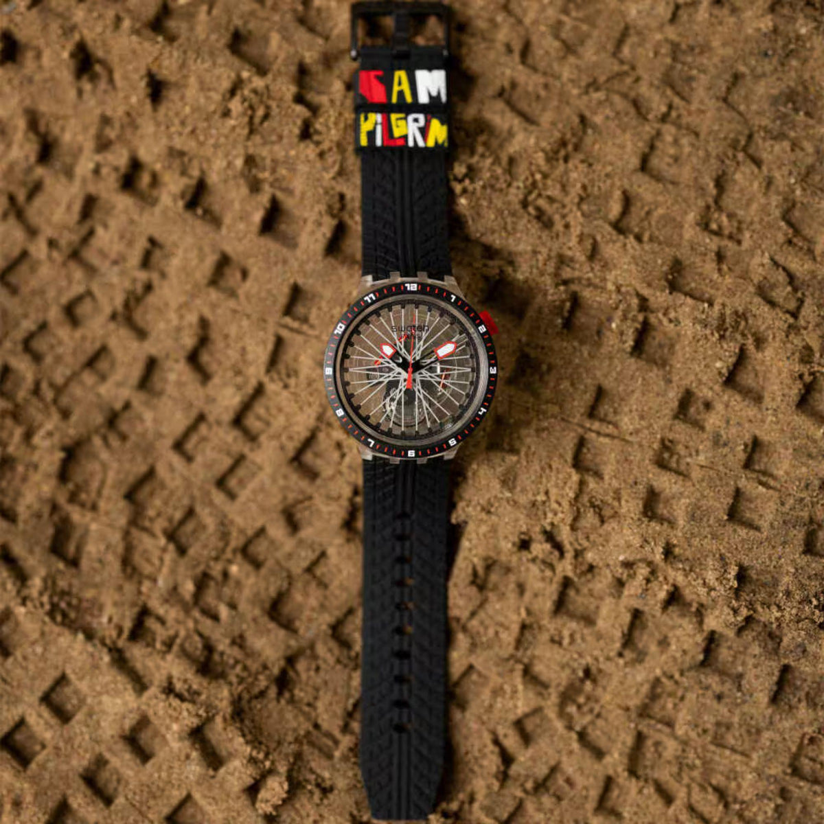 Swatch wristwatch with transparent dial, red hands, black silicone strap on textured background