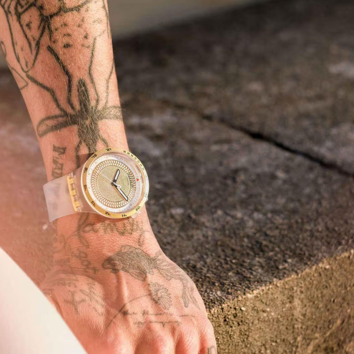 Gold-tone mens watch with golden textured dial and white silicone strap on wrist