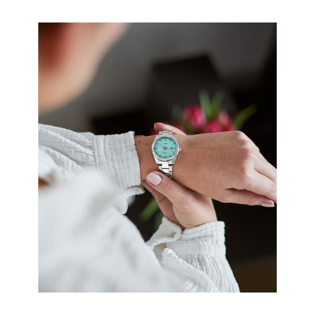 Analog quartz watch on wrist, steel bracelet and turquoise dial, silver case