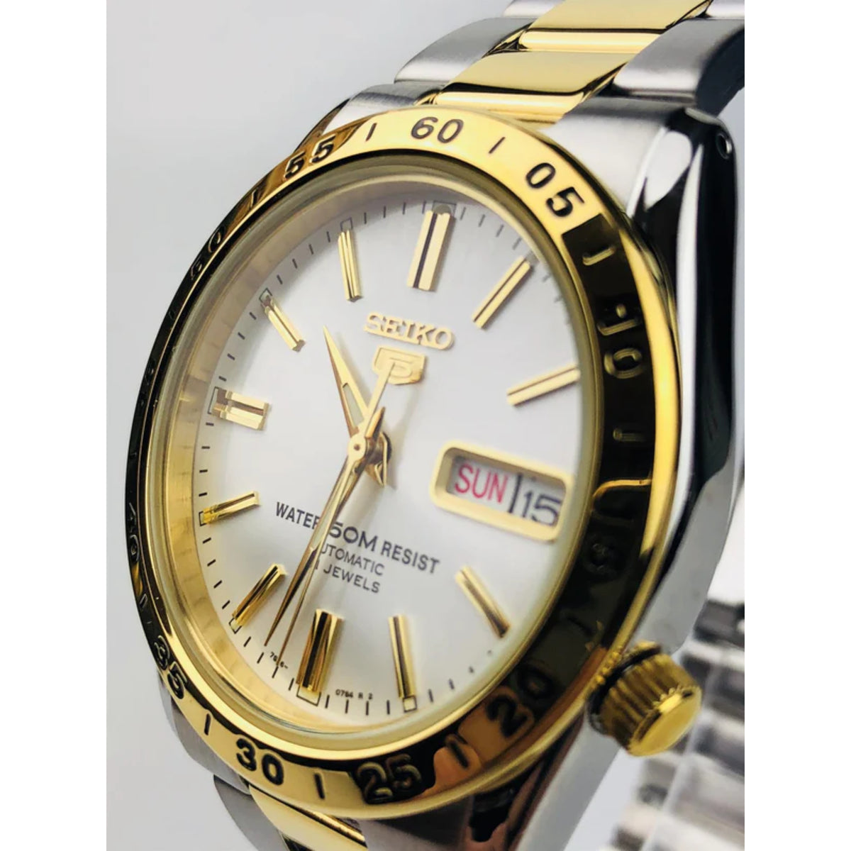 Two-tone Seiko automatic watch close-up, white dial, gold bezel, and day date window