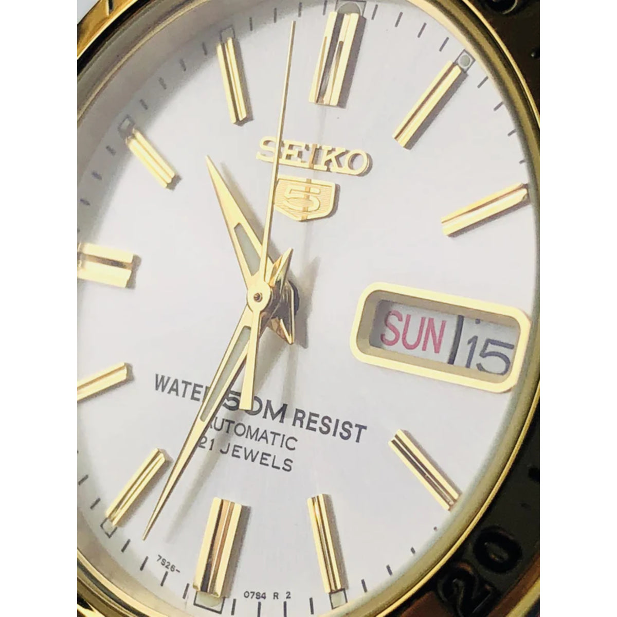 Close-up of Seiko white dial with gold markers, hands, and SUN 15 day-date window
