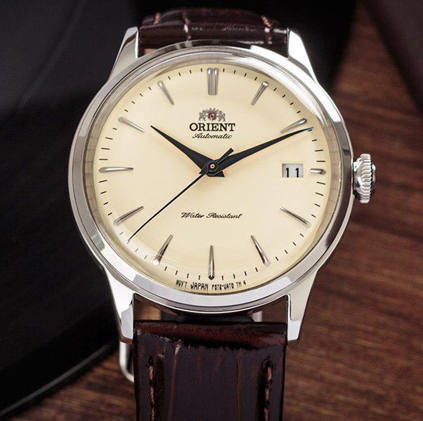 Orient automatic wristwatch close-up: cream dial with blue hands, brown leather strap