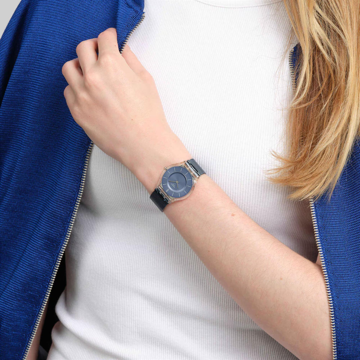 Men’s wristwatch with blue dial and dark blue mesh strap worn on a woman’s wrist