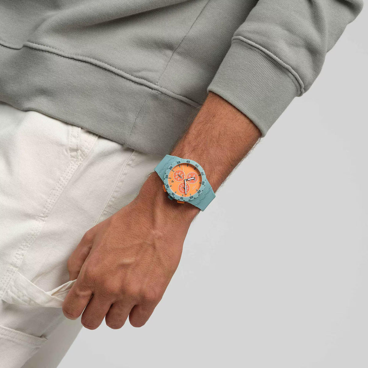 Quartz orange dial silicone strap watch on wrist, teal case and orange subdials