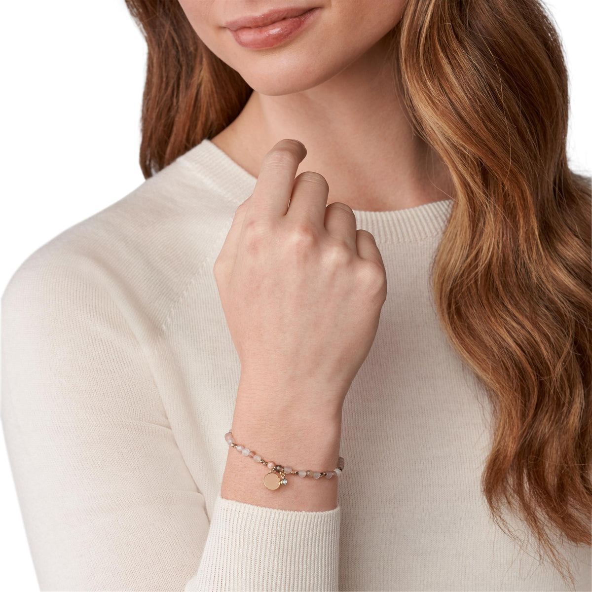 Beaded moonstone bracelet on wrist with small oval charm and crystal detail