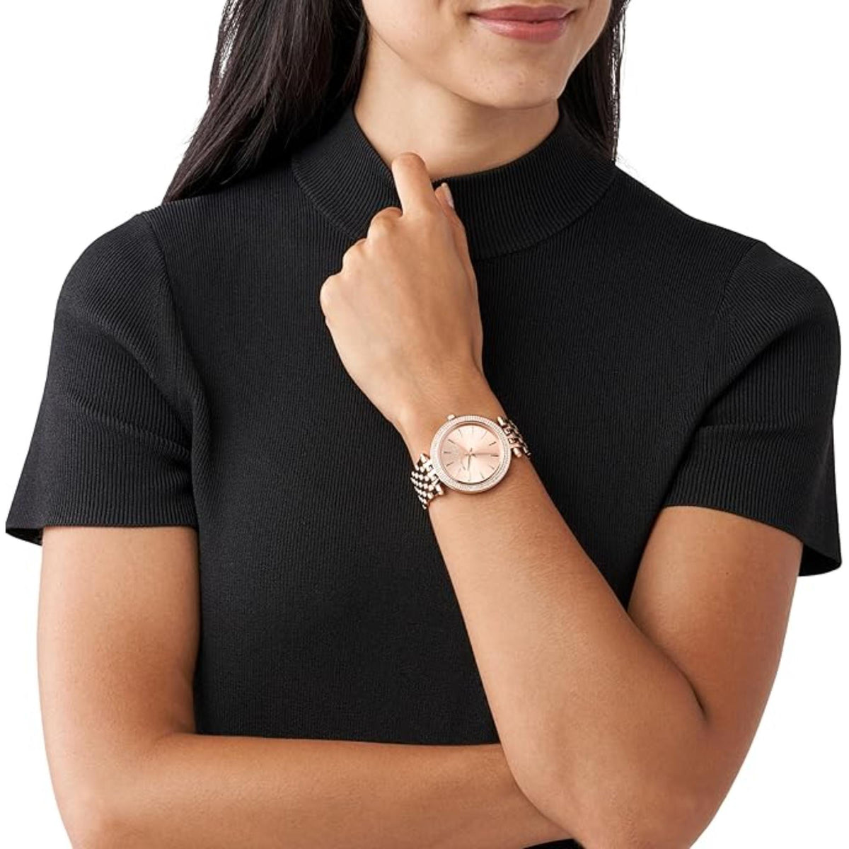 Women’s rose-gold watch on wrist with textured steel link bracelet