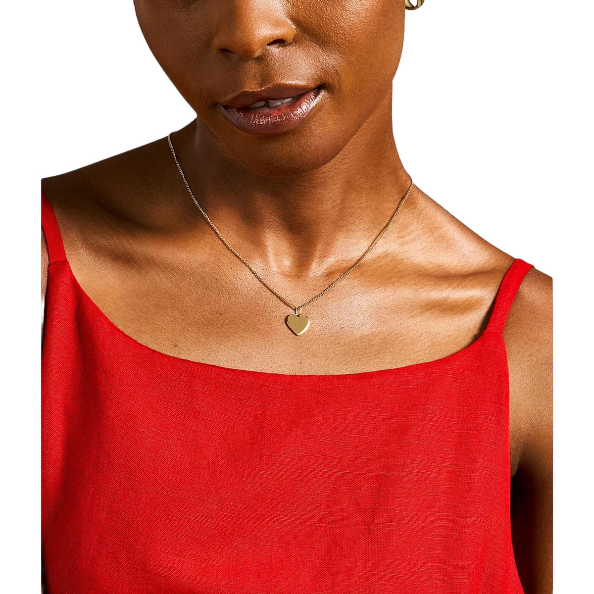 Gold-tone heart pendant necklace worn on model with fine chain