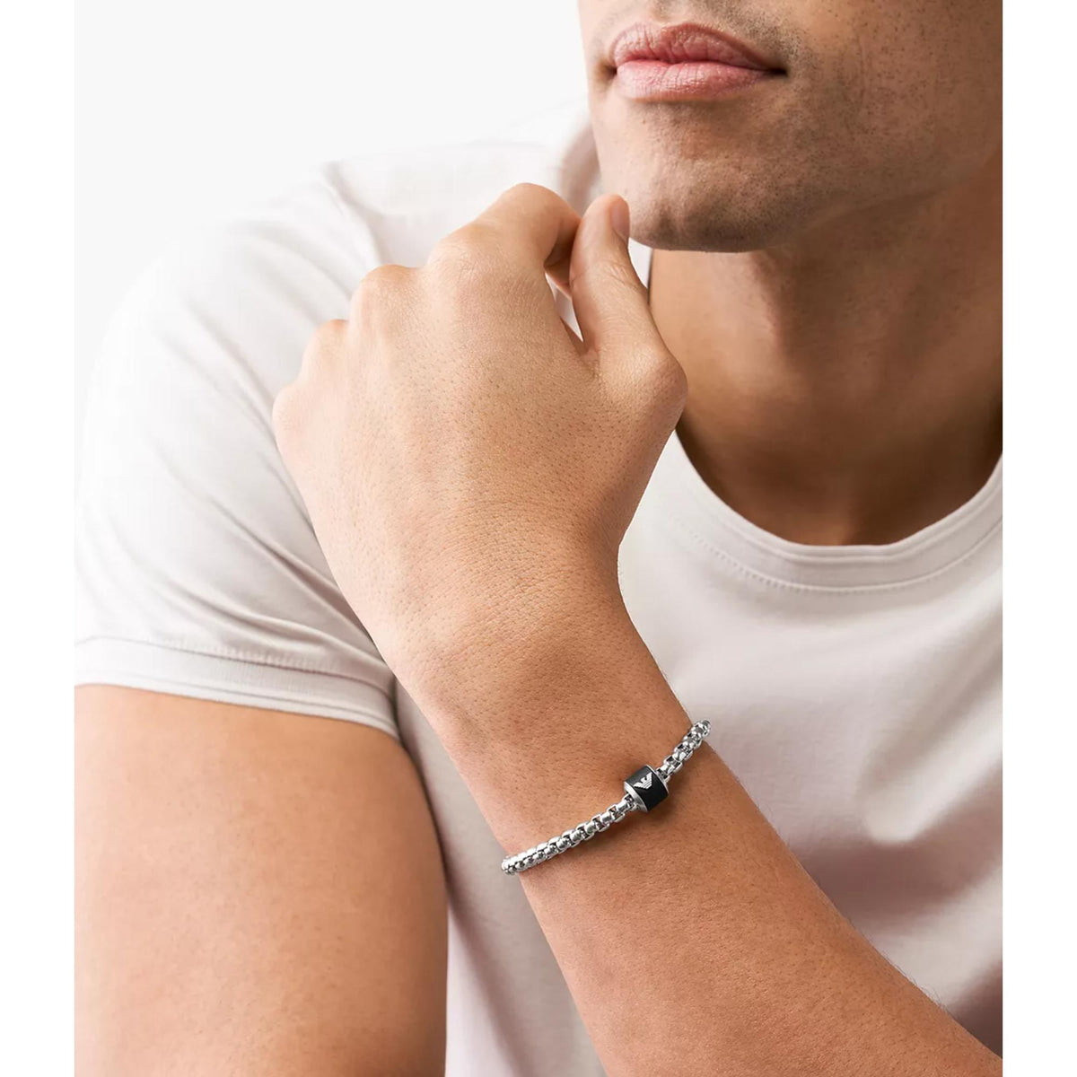 Silver chain bracelet with black square logo centerpiece worn on wrist