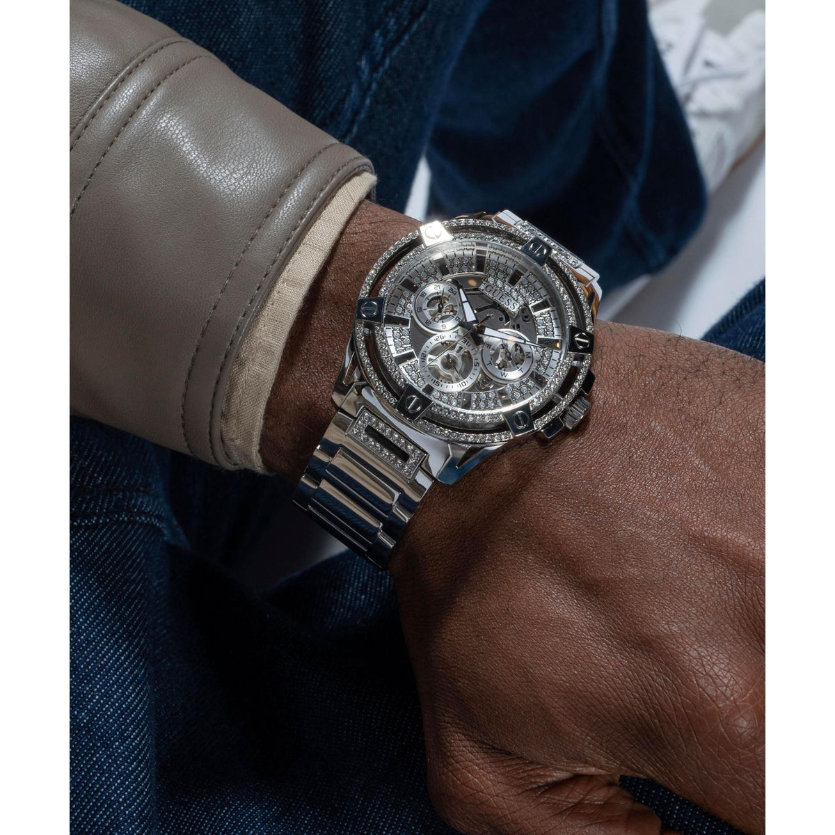 Silver crystal multifunction watch on wrist with steel bracelet and patterned dial