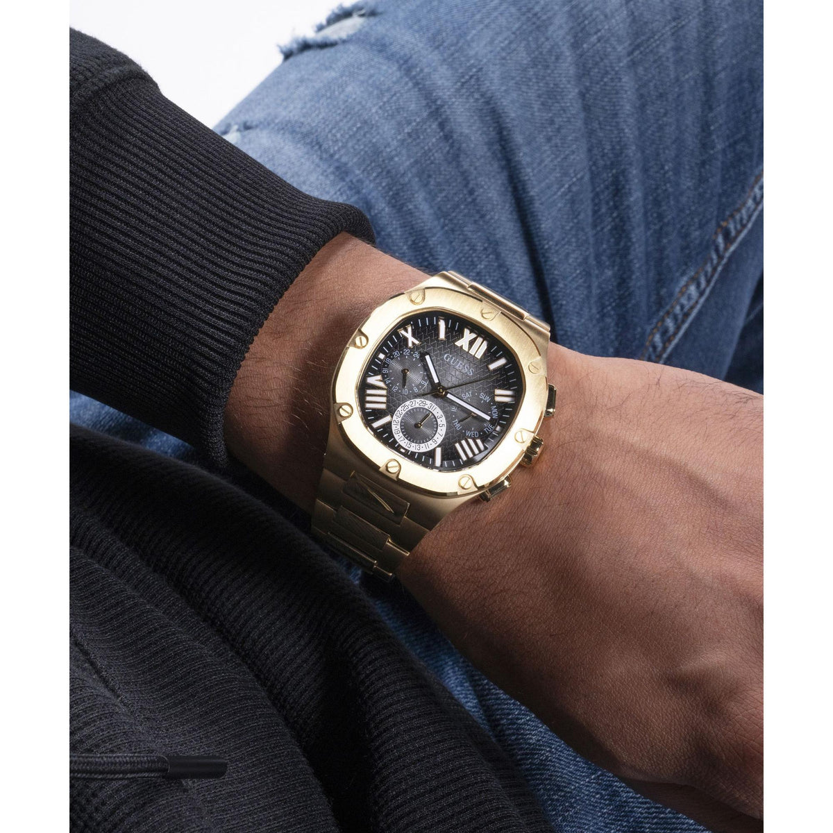 Gold tone men's watch on wrist, black dial with Roman numerals and a subdial at 6