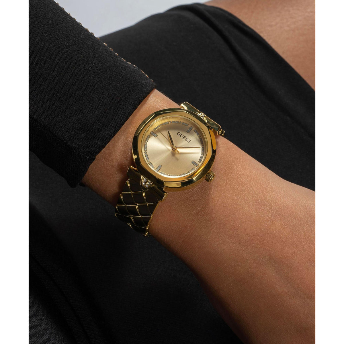 Gold-tone women's wrist watch with textured bracelet and gold dial on arm.