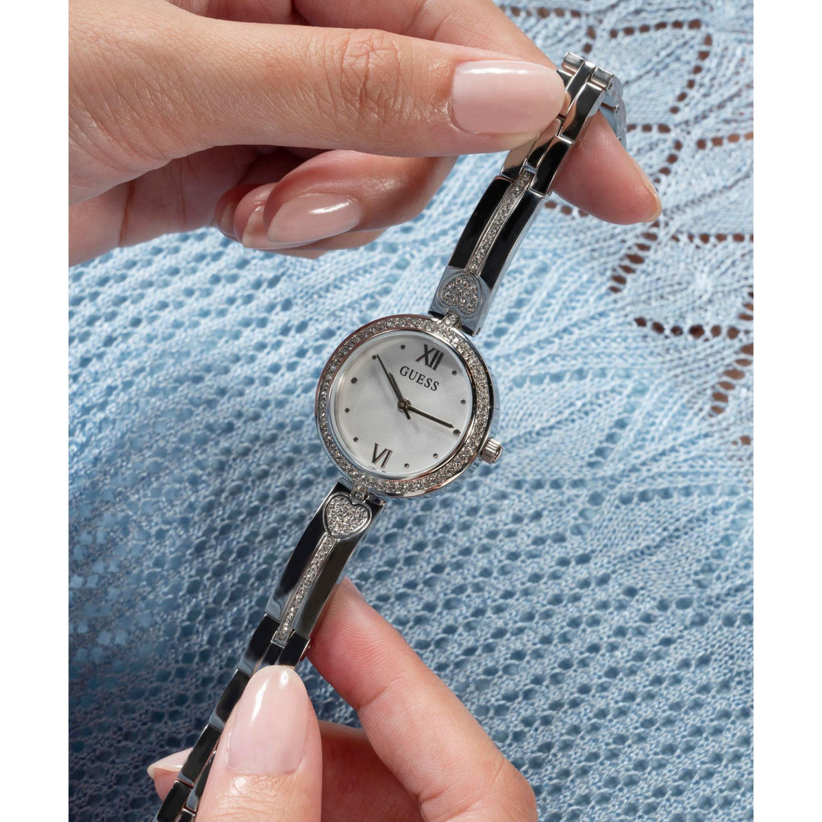 Silver-tone analog watch on wrist, white dial and crystal bezel with heart-shaped charm