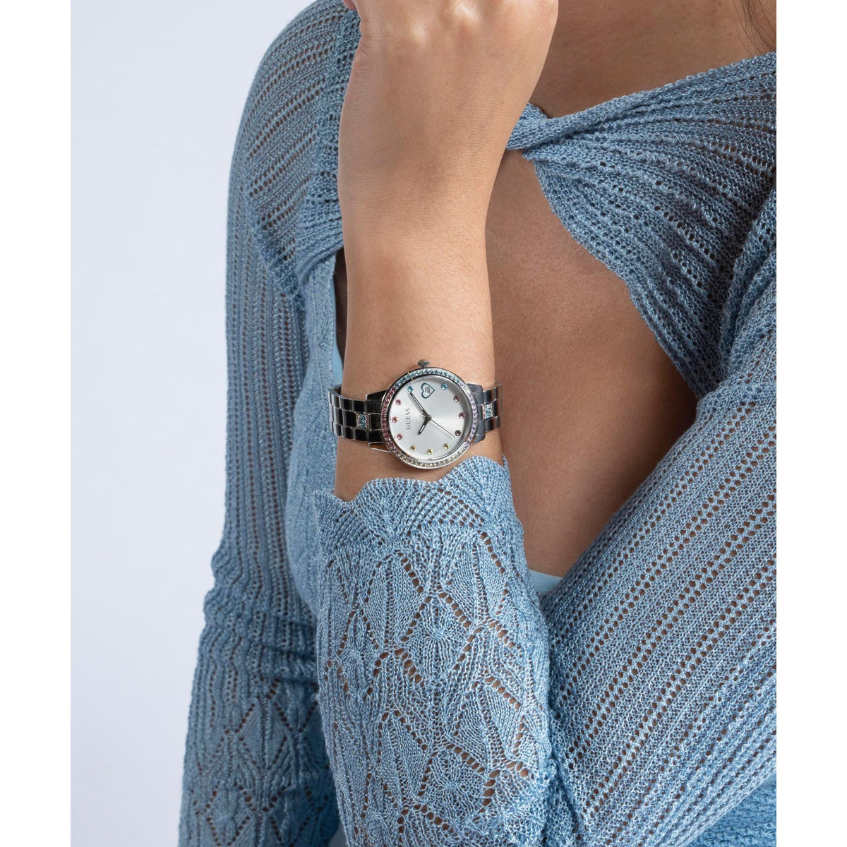Ladies silver quartz watch on wrist with white dial, blue heart details, steel band