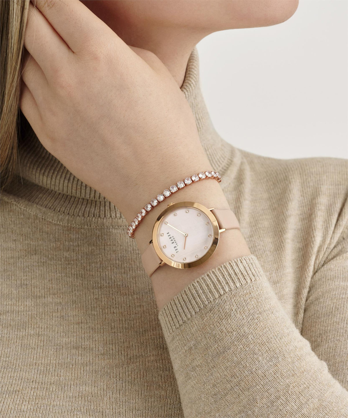 Ladies leather strap watch on wrist with pale pink strap, gold-tone case, crystal bezel