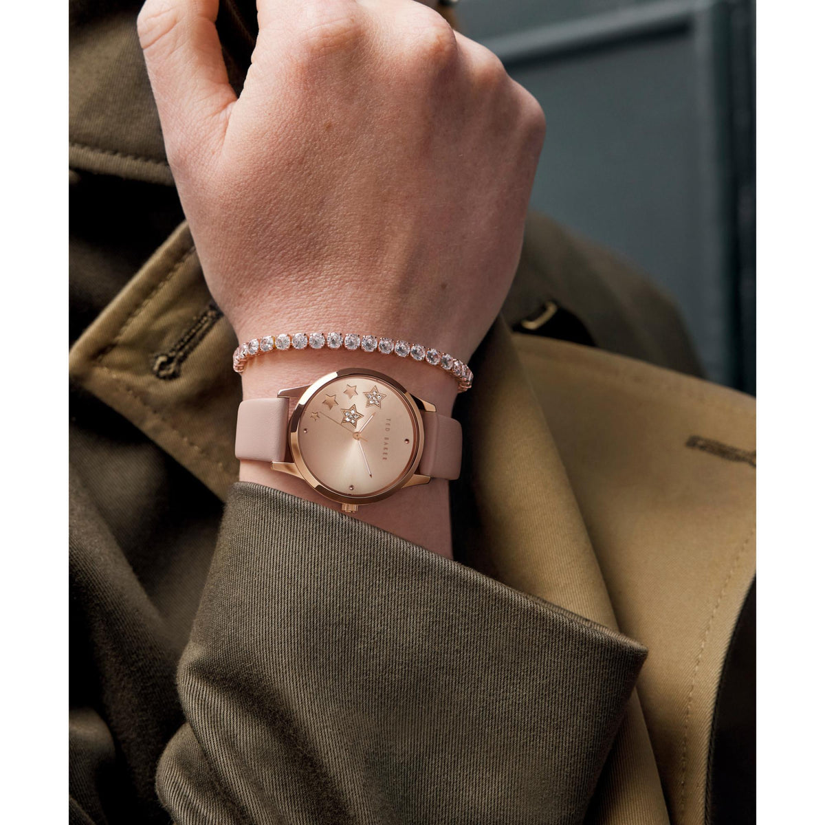 Pink strap star dial watch on wrist, with rhinestone hoop charm bracelet