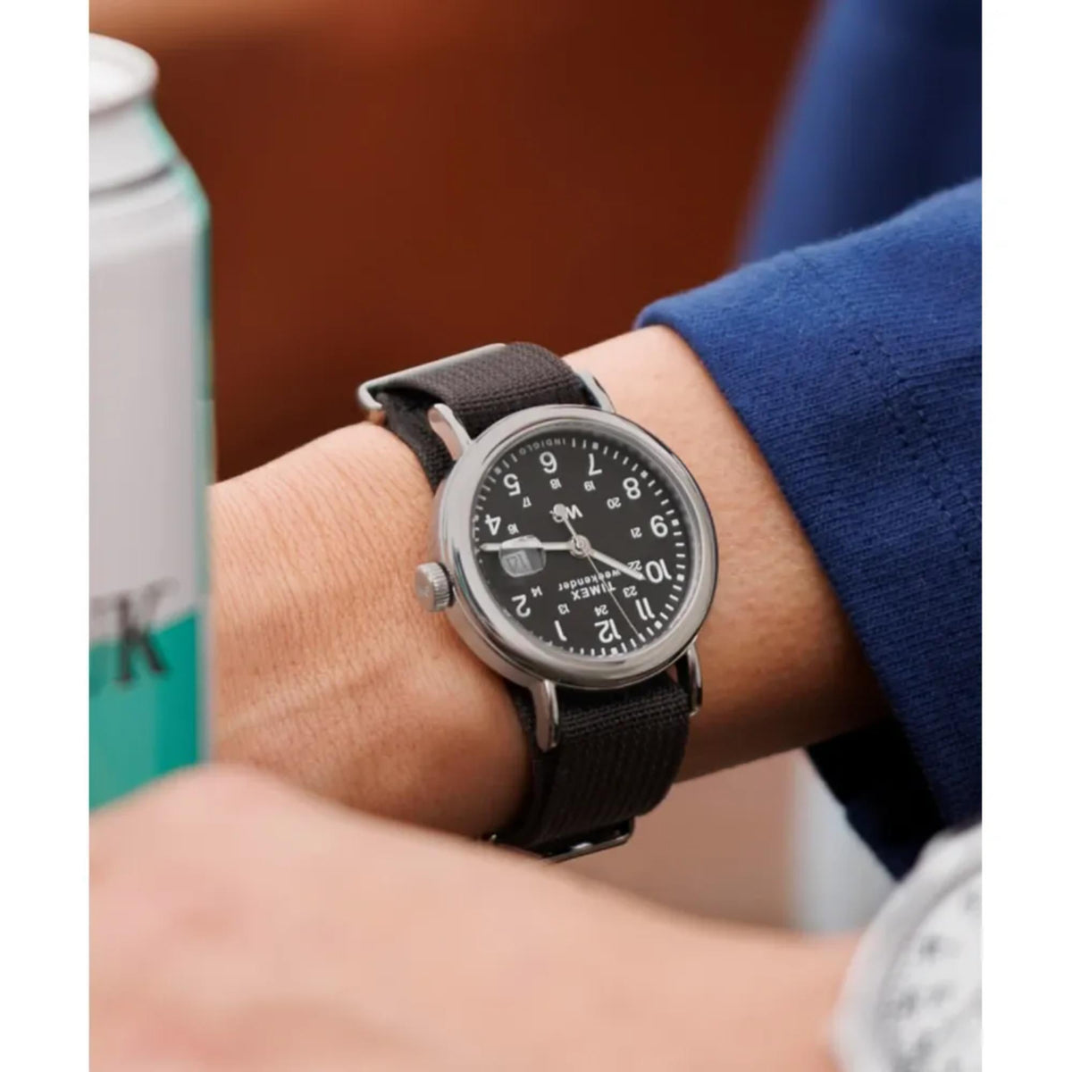 Men’s wrist watch with black dial and black fabric strap on an arm