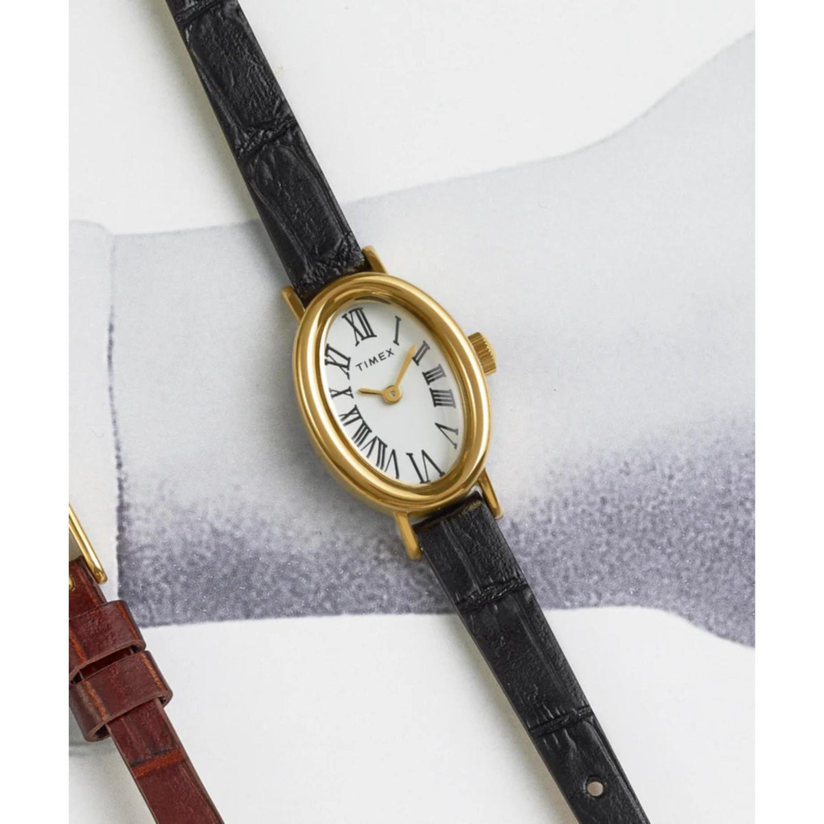 Close view of ladies watch face with Roman numeral markers, gold-tone case, black leather band