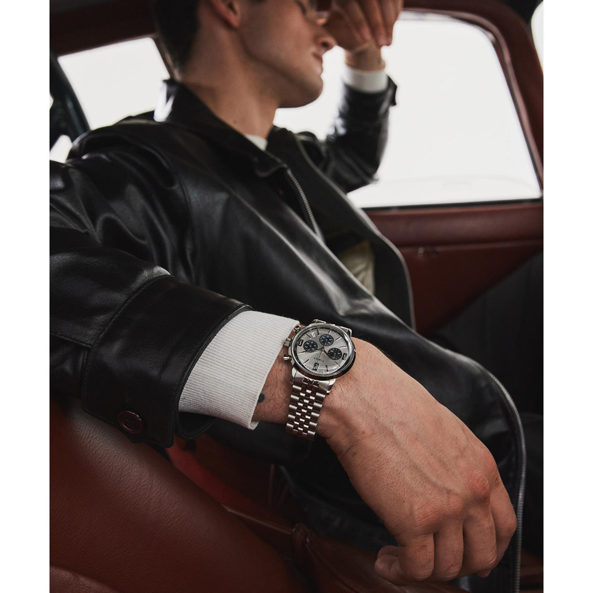 Men's silver steel Timex chronograph quartz watch worn on wrist with black leather jacket