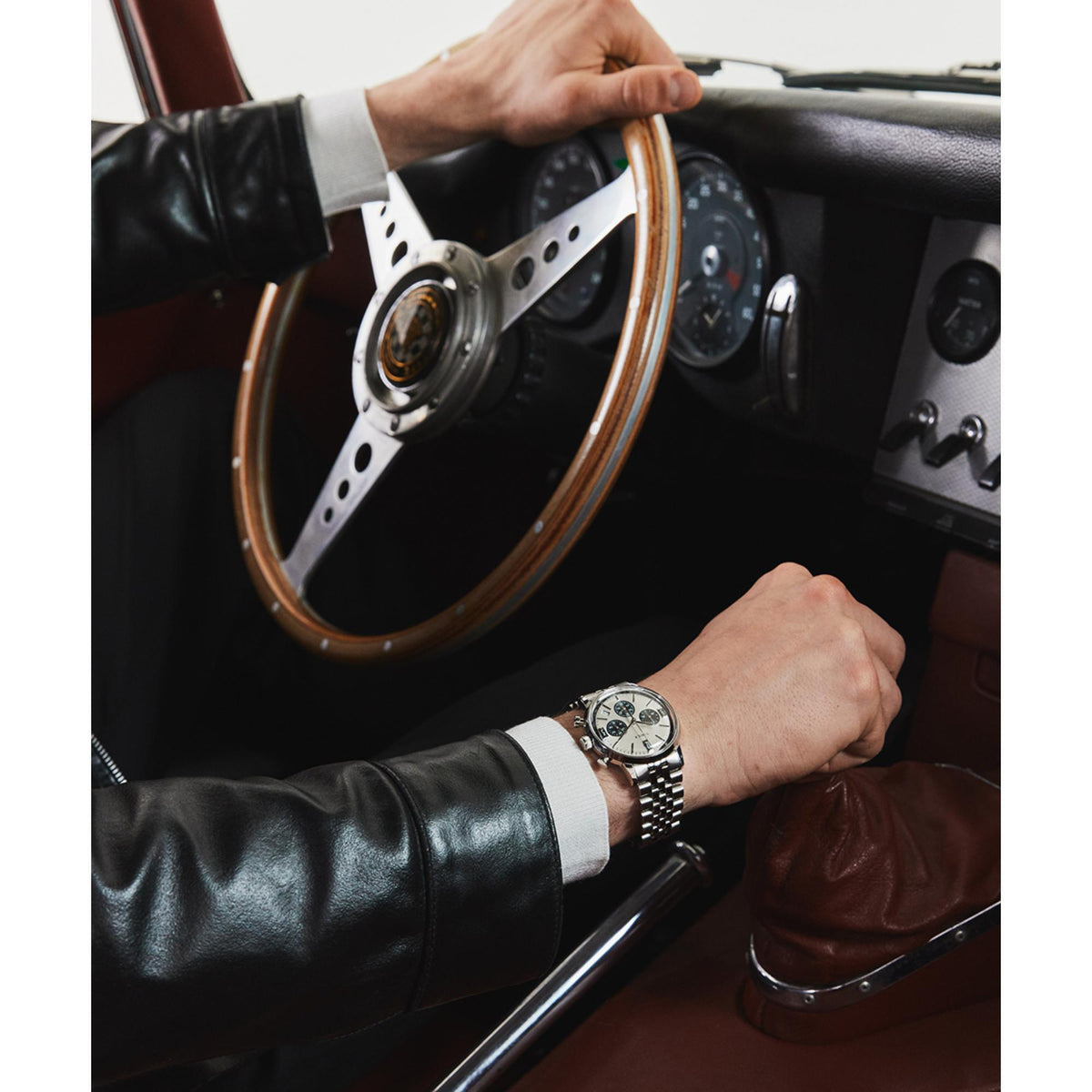 Men's silver steel Timex chronograph quartz watch on wrist while driving, steering wheel visible