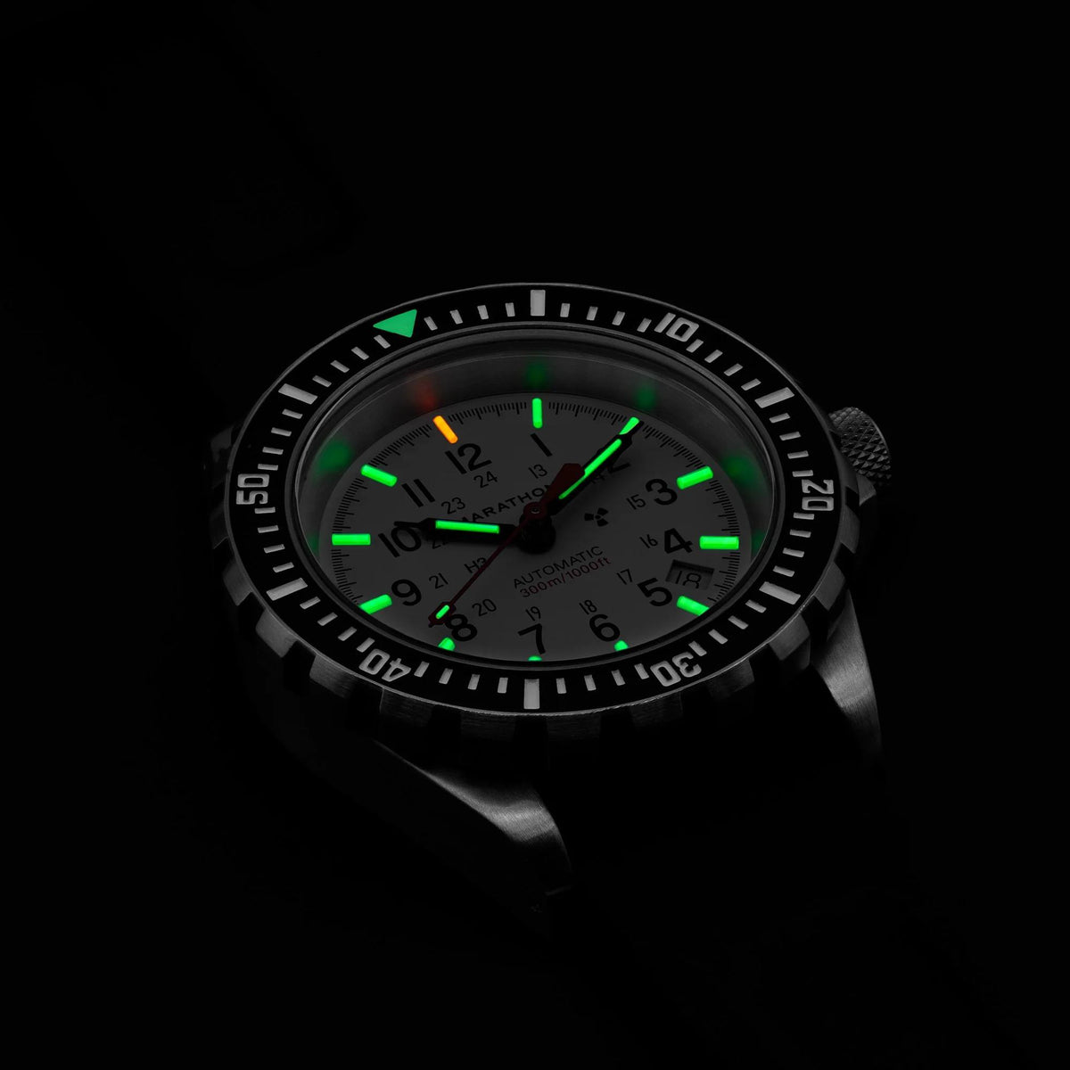 Dive watch in low light with green luminous markers and hands on dark bezel