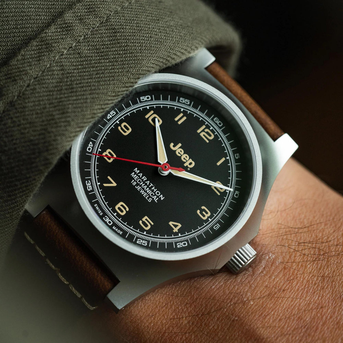 Men's mechanical watch on wrist with black dial, brown leather strap and metal bezel