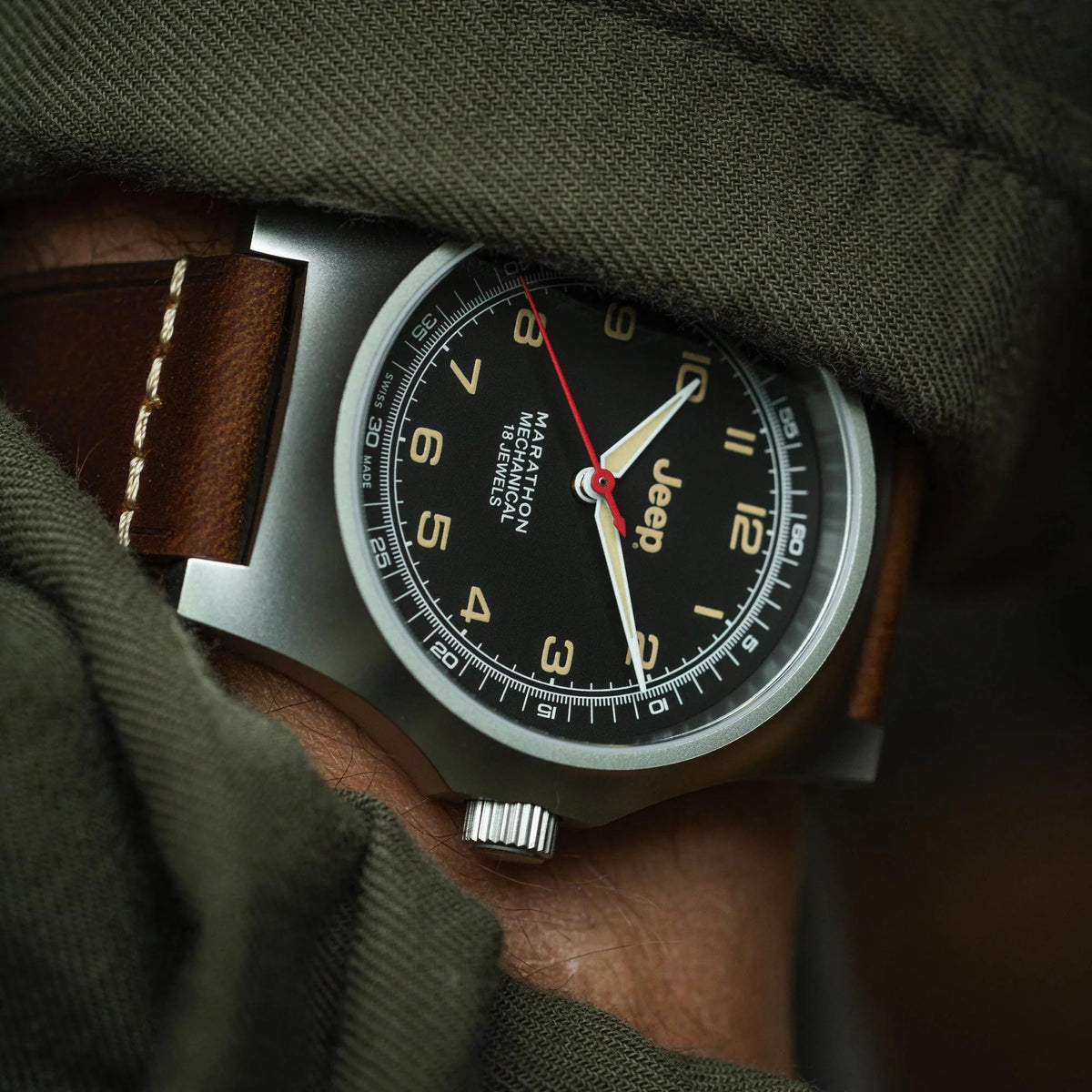 Men's mechanical watch on wrist with black dial, brown leather strap and visible crown