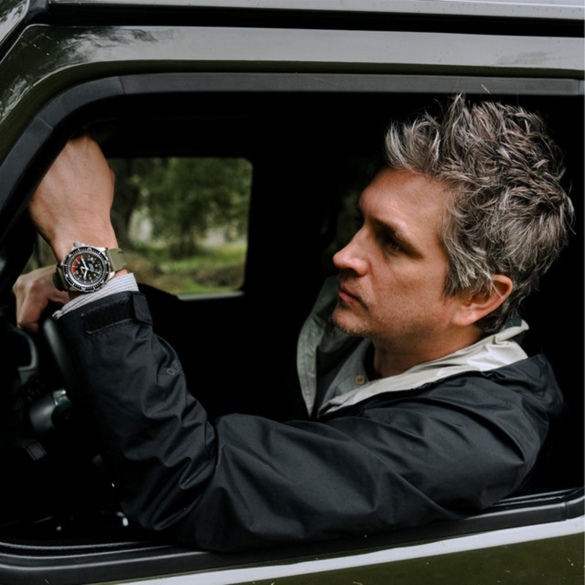 Men's diver watch on wrist with black dial, stainless steel case, olive silicone strap