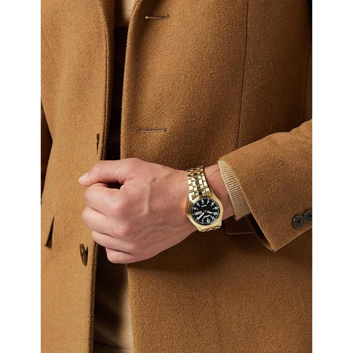 Gold-tone watch on wrist with black dial and date window, set in a linked metal bracelet
