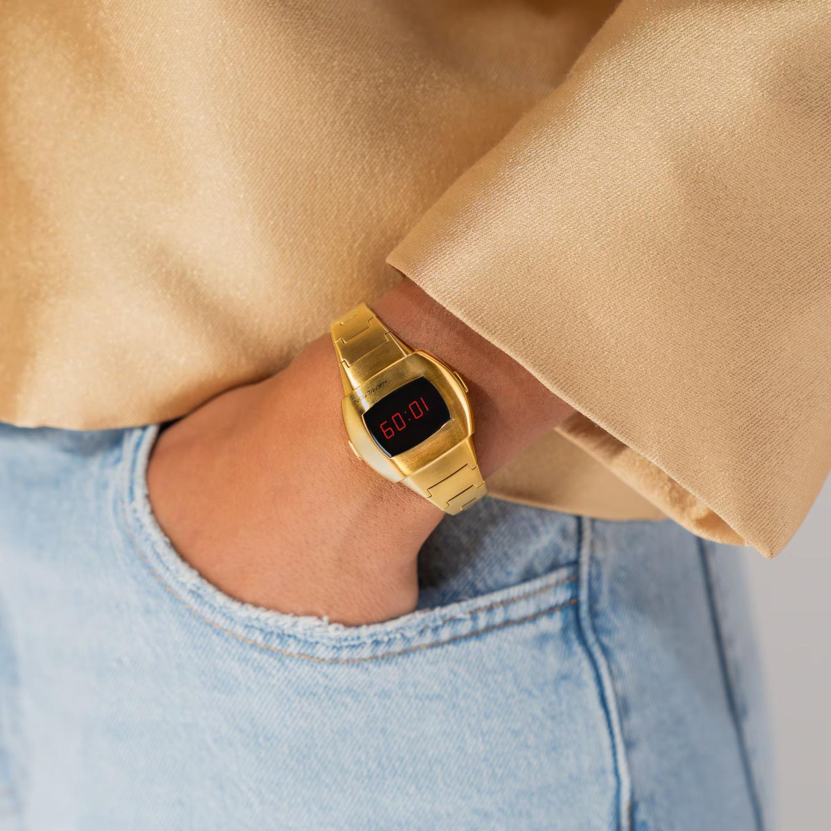 Gold digital watch on wrist with black face and red time digits