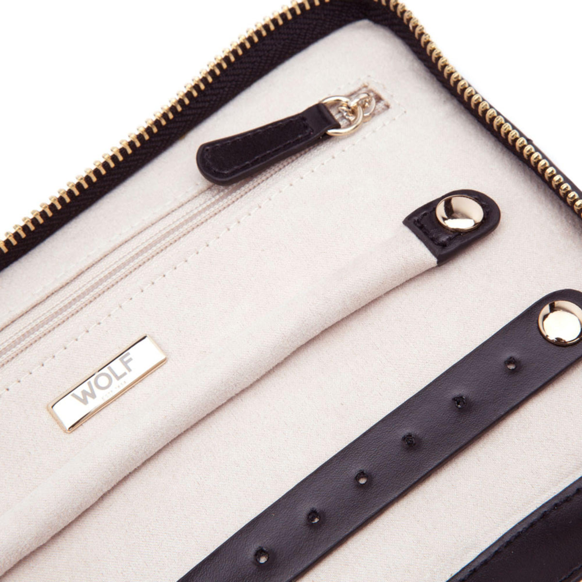 Interior close-up of black portfolio: cream panels, Wolf logo, and gold zipper edge.