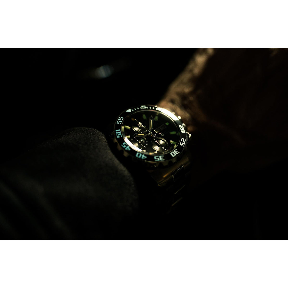 Men's diver watch close-up with black dial and glowing bezel numerals