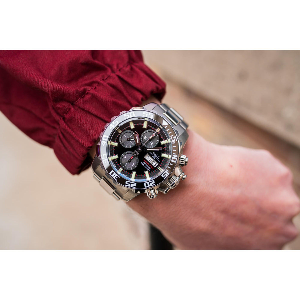 Men's chronograph diver watch on wrist, black dial with luminous bezel and metal bracelet