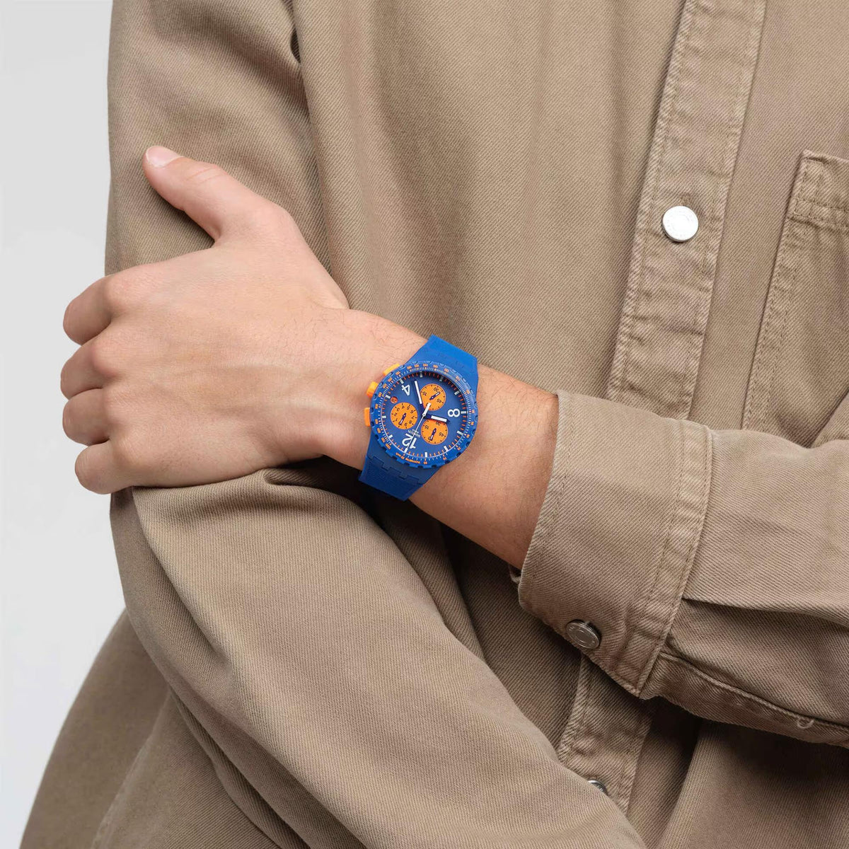 Blue chronograph watch on wrist with orange dial details and silicone strap