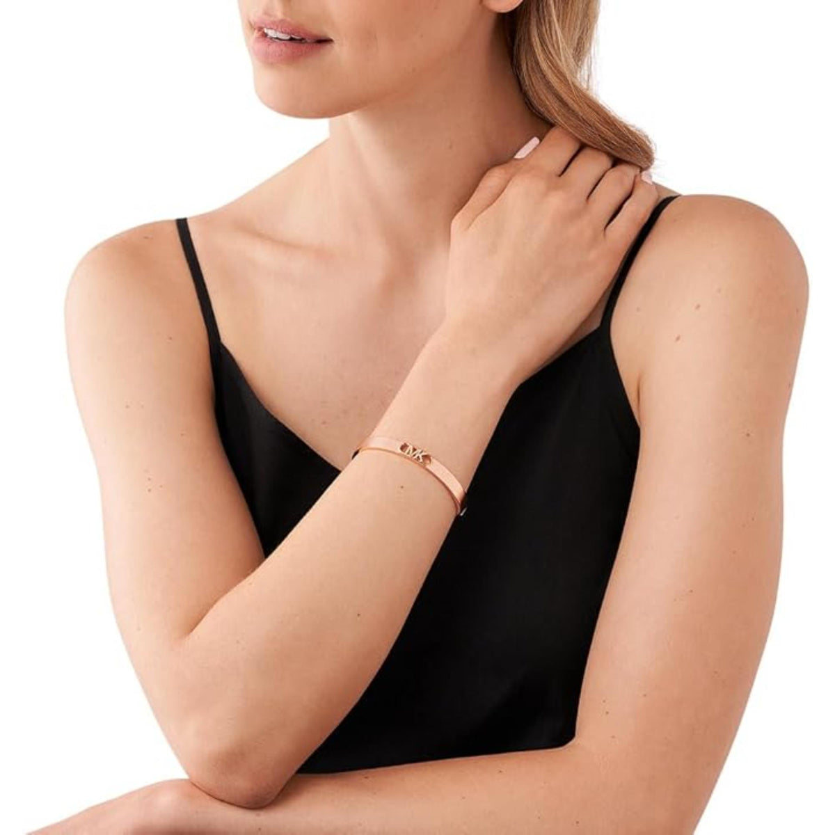 Rose gold-plated bangle bracelet on wrist with small MK emblem center